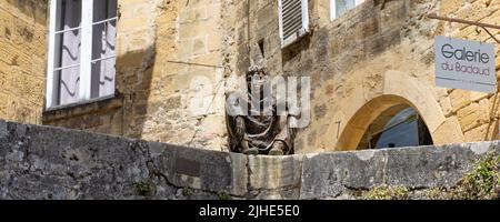 Sarlat-la-Caneda, Frankreich - April 30 2022: Le Badaud die Schauerskulptur mit Blick auf den malerischen mittelalterlichen Platz im historischen Zentrum von Sarlat. Stockfoto