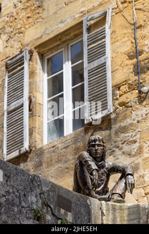 Sarlat-la-Caneda, Frankreich - April 30 2022: Le Badaud die Schauerskulptur mit Blick auf den malerischen mittelalterlichen Platz im historischen Zentrum von Sarlat. Stockfoto