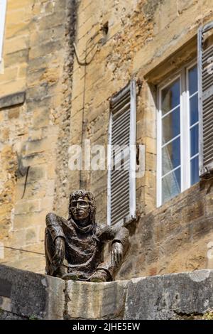 Sarlat-la-Caneda, Frankreich - April 30 2022: Le Badaud die Schauerskulptur mit Blick auf den malerischen mittelalterlichen Platz im historischen Zentrum von Sarlat. Stockfoto