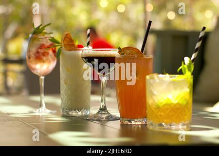 Verschiedene bunte Cocktails auf einem Tisch vor verschwommenem Hintergrund Stockfoto