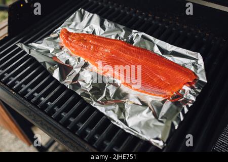 Lachsfilet auf Folie auf Barbecue-Grill Stockfoto