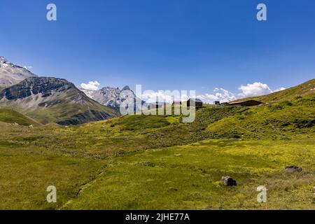 Luftaufnahme einer sehr großen und majestätischen alpinen Landschaft im Herr der Ringe Stil. In der Mitte befindet sich ein kleines Bergdorf, das hauptsächlich aus Almen besteht. Stockfoto