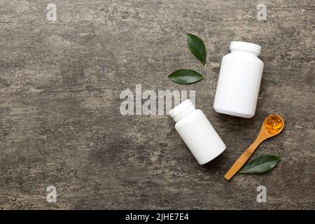 Omega-3 Kapseln liegen in einer weißen Flasche auf einem Tisch mit grünem Blatthintergrund. Fischöltabletten. Biologisch aktive Zusatzstoffe. omega 6, Omega 9, Vitam Stockfoto