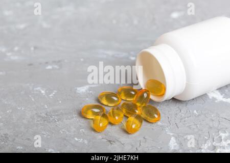 Omega-3 Kapseln liegen in einer weißen Flasche auf einem Tischhintergrund. Fischöl Tabletten Draufsicht. Biologisch aktive Zusatzstoffe. omega 6, Omega 9, Vitamin A, E, Stockfoto