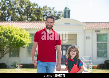 Vater unterstützt und motiviert Sohn. Kind geht zur Grundschule. Stockfoto