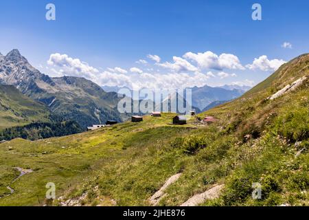 Luftaufnahme einer sehr großen und majestätischen alpinen Landschaft im Herr der Ringe Stil. In der Mitte befindet sich ein kleines Bergdorf, das hauptsächlich aus Almen besteht. Stockfoto