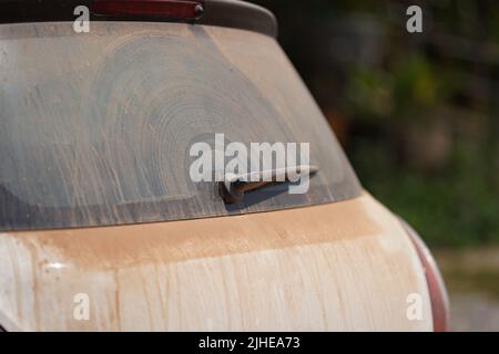 Viel rotbrauner Staub auf der Rückseite Spiegel Auto mit einem Schneebesen davon. Stockfoto