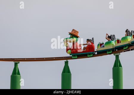 Southend-on-Sea, Großbritannien Juli 17. 2022 Kinder auf einer Achterbahn mit Krokodil-Zeichentrickfigur in einem Hauptauto. Isoliert vor klarem Himmel Hintergrund. Gr Stockfoto