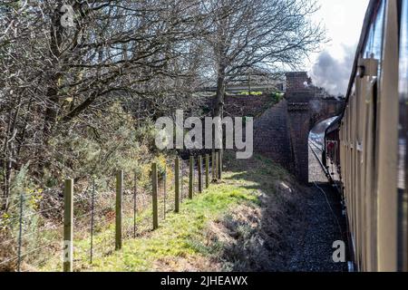 ‘Black Prince’ BR-9F-92203 geht unter einer Straßenbrücke, nachdem er holt Station auf der Poppy Line, North Norfolk Railway, East Anglia, England, Großbritannien, verlassen hat. Stockfoto