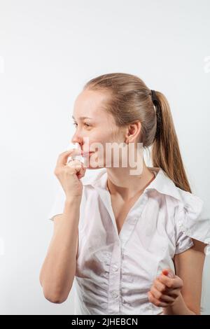 Das Mädchen tropft Nasentropfen aus einer laufenden Nase mit Influenza Stockfoto