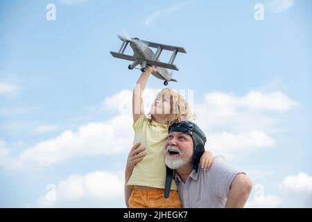 Großvater und Enkel genießen das gemeinsame Spielen mit dem Flugzeug am blauen Himmel. Nettes Kind mit Großvater spielt draußen. Stockfoto