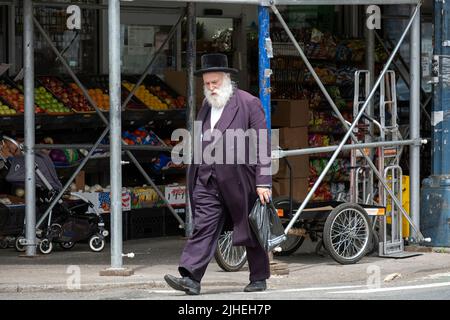 Ein chassidischer jüdischer Mann geht auf der Lee Avenue spazieren, nachdem er ein paar Einkäufe gemacht hat. In Williamsburg, Brooklyn, New York City. Stockfoto