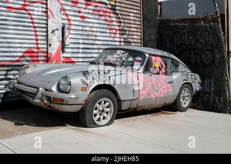 STADTLANDSCHAFT. Eine graffierte und reckte Jaguar Limousine in der Roebling Street in Williamsburg, Brooklyn, New York. Stockfoto