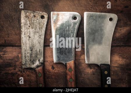 Tischbild von drei Vintage-Spaltsteinen zum Fleischhacken mit scharfer Klinge, Küchenmesser-Konzept Stockfoto