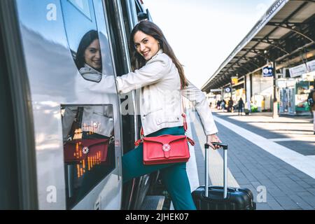 Junge Geschäftsfrau, die am Bahnhofseingang steht und auf der Suche nach jemandem im Bahnhof ist - ein schöner Reisender Stockfoto