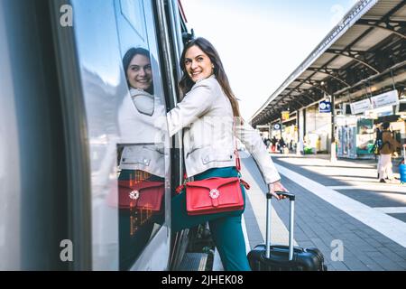 Junge Geschäftsfrau, die am Bahnhofseingang steht und auf der Suche nach jemandem im Bahnhof ist - ein Zeichen dafür, dass eine schöne Reisende Frau bekommt Stockfoto