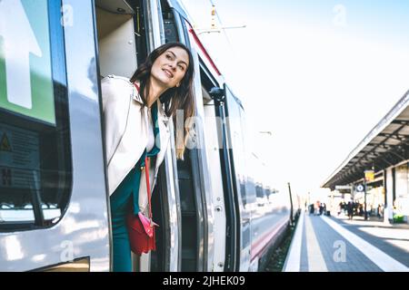 Junge Geschäftsfrau, die am Bahnhofseingang steht und auf der Suche nach jemandem im Bahnhof ist - ein Zeichen dafür, dass eine schöne Reisende Frau bekommt Stockfoto