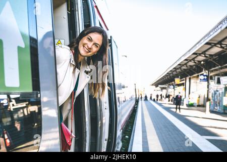 Junge Geschäftsfrau, die am Bahnhofseingang steht und auf der Suche nach jemandem im Bahnhof ist - ein Zeichen dafür, dass eine schöne Reisende Frau bekommt Stockfoto