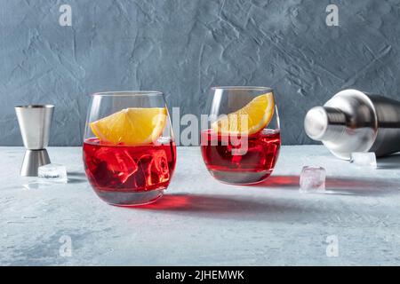 Campari-Aperitif mit frischen Orangenscheiben, einem Jigger und einem Shaker. Ein Sommercocktail mit Eis Stockfoto