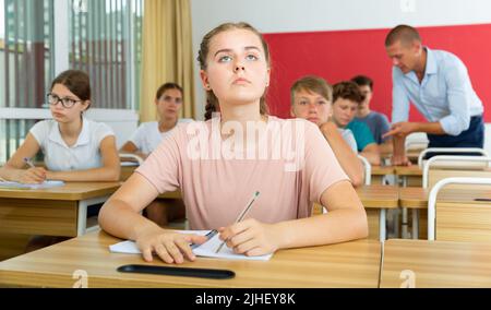 Teen Mädchen hören Dozent und schriftlich in Notebook im Klassenzimmer Stockfoto