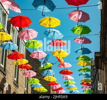 Aberdeen, Schottland, Großbritannien – Juni 26 2022. Farbenfrohe Regenschirme, die im Rahmen des Neurodiversity Umbrella Project über einer belebten Stadtstraße aufgehängt werden Stockfoto