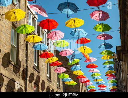 Aberdeen, Schottland, Großbritannien – Juni 26 2022. Farbenfrohe Regenschirme, die im Rahmen des Neurodiversity Umbrella Project über einer belebten Stadtstraße aufgehängt werden Stockfoto