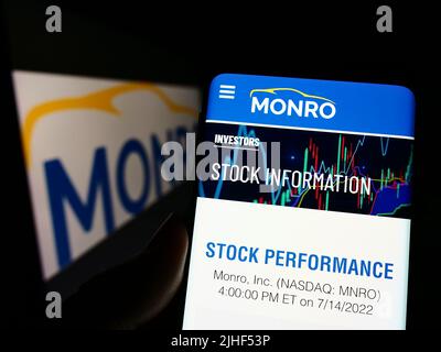 Person mit Smartphone und Webseite des US-amerikanischen Automobildienstleisters Monro Inc. Auf dem Bildschirm vor dem Logo. Konzentrieren Sie sich auf die Mitte des Telefondisplays. Stockfoto