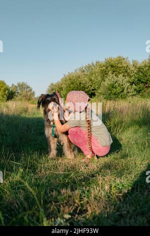 Kleines Mädchen umarmt spielen mit Hund im Freien. Familienspaziergängen Spaß haben Zeit zusammen in der Natur zu verbringen. Kind mit Haustier Freund auf Sommerwiese. Acti Stockfoto