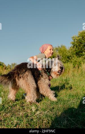 Kleines Mädchen umarmt spielen mit Hund im Freien. Familienspaziergängen Spaß haben Zeit zusammen in der Natur zu verbringen. Kind mit Haustier Freund auf Sommerwiese. Acti Stockfoto