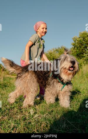 Kleines Mädchen umarmt spielen mit Hund im Freien. Familienspaziergängen Spaß haben Zeit zusammen in der Natur zu verbringen. Kind mit Haustier Freund auf Sommerwiese. Acti Stockfoto