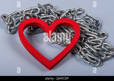 Herzform mit metallischer Kette auf blauem Hintergrund Stockfoto