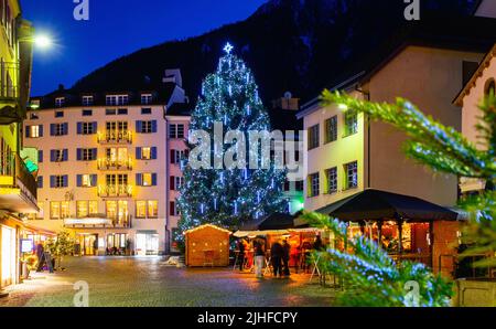 Nachtansicht der Brig Straße mit Weihnachtsbaum im Hintergrund der Alpen, Schweiz Stockfoto