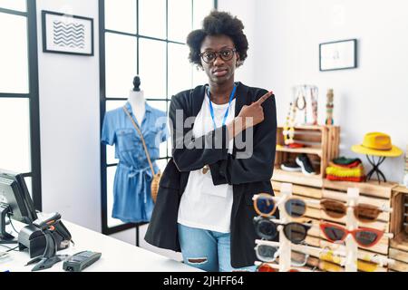 Afrikanische junge Frau, die als Managerin in einer Einzelhandelsboutique arbeitet und mit dem Finger auf die Seite zeigt, die Werbung zeigt und ein ernstes und ruhiges Gesicht zeigt Stockfoto