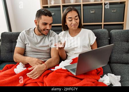 Junge lateinamerikanische kranke Paare, die zu Hause eine medizinische Fernsulation mit einem Laptop haben. Stockfoto