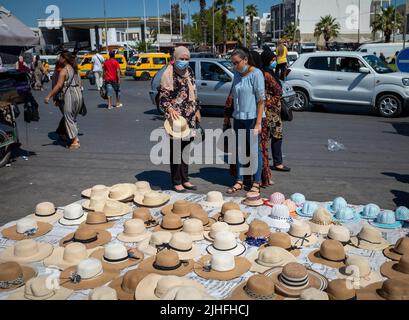 Frauen halten an, um sich einen Stand anzusehen, der Hüte auf dem Sunday Souk verkauft, einem Wochenmarkt in Sousse, Tunesien. Stockfoto