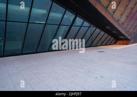 Rückwand mit einem Parkplatz auf dem Hintergrund eines modernen, futuristischen Gebäudes aus Stahl und Glas Stockfoto