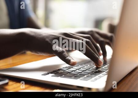 Bild der Hände eines afroamerikanischen Mannes, der auf einem Laptop arbeitet Stockfoto