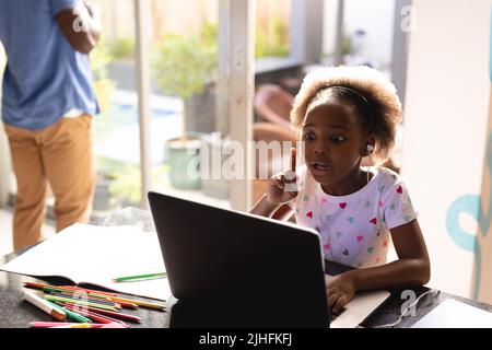 Bild von afroamerikanischem Vater und Tochter, die online Unterricht haben und zusammenarbeiten Stockfoto