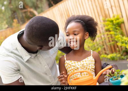 Bild eines glücklichen afroamerikanischen Vaters und einer Tochter, die gemeinsam gärtnerisch arbeiten Stockfoto