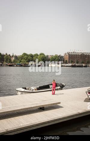 An einem heißen und sonnigen Tag in Amsterdam, Niederlande, hält eine Frau die Anlegestelle eines Motorbootes an einem Kanal. Stockfoto