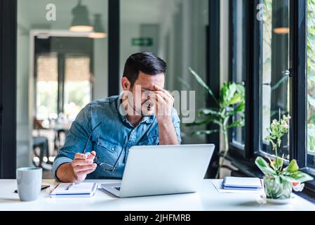 Müde junge Mann fühlen Schmerzen Augen Belastung halten Brille reiben trocken reizte Augen müde von Computer-Arbeit. Gestresster Mann leiden unter Kopfschmerzen Bad visi Stockfoto
