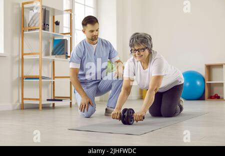 Ältere Frau, die im Physiotherapieraum mit Bauchrolle Sport macht Stockfoto