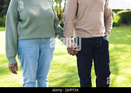 Bild des mittleren Teils des afroamerikanischen Seniorenpaares im Garten Stockfoto