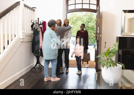 Bild einer glücklichen, mehrgenerationenigen afroamerikanischen Familie, die das Haus betreten und sich gegenseitig willkommen heißen Stockfoto
