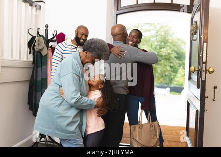 Bild einer glücklichen, mehrgenerationenigen afroamerikanischen Familie, die das Haus betreten und sich gegenseitig willkommen heißen Stockfoto