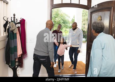 Bild einer glücklichen, mehrgenerationenigen afroamerikanischen Familie, die das Haus betreten und sich gegenseitig willkommen heißen Stockfoto