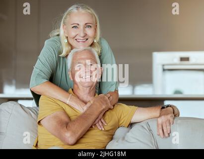 Glückliches älteres Paar verbindet sich und genießt gemeinsam den Ruhestand. Ältere kaukasische Männer und Frauen, die zu Hause auf einem Sofa anhänglich sind Stockfoto