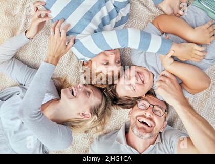 Sorgenfrei liebende Eltern von oben kitzeln und necken ihre niedlichen kleinen lachenden Söhne. Glückliche kaukasische vierköpfige Familie, die sich entspannt und zusammen spielt Stockfoto