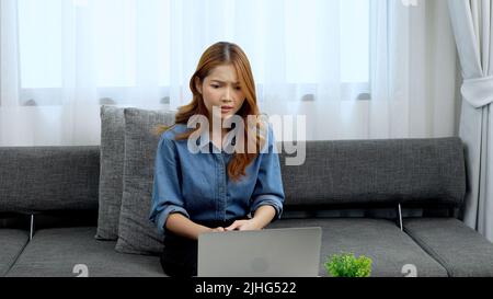 Eine verwirrte junge Frau, die vor ihrem Laptop sitzt Stockfoto