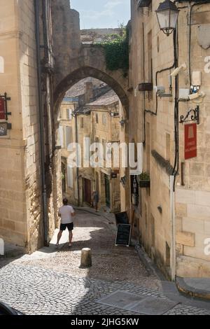 Mann, der auf den alten Torbogen blickt, der als Cadence Gate in einer engen gepflasterten Straße in Saint Emilion France bekannt ist Stockfoto